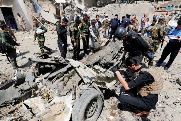 Iraqi security forces inspect the site of a car bomb attack in Jamila market in Sadr City district of Baghdad