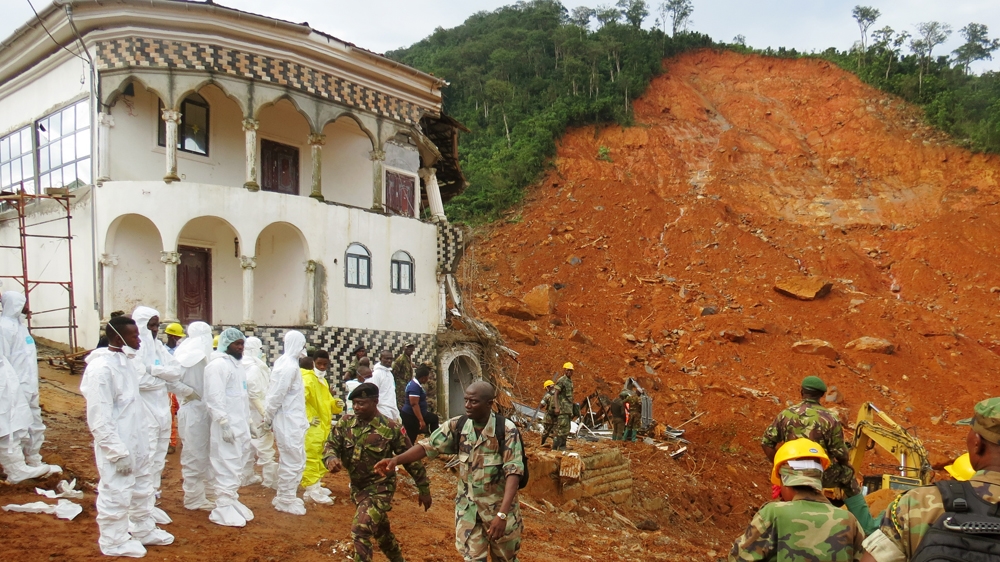 Search and rescue team members and soldiers operate near a mudslide site and damaged building near Freetown on August 15, 2017, after landslides struck the capital of the West African state, Sierra Leone [Saidu Bah/AFP] 