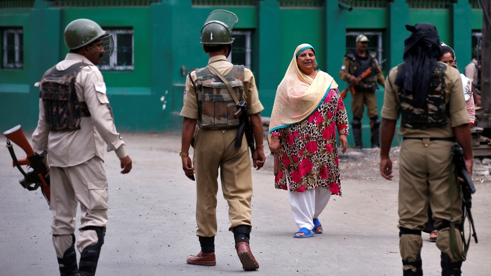 Indian policemen stop Kashmiri women during a curfew in the downtown area of Srinagar on July 21, 2017 [Danish Ismail/Reuters]