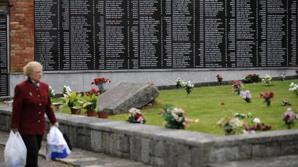 A woman walks past a memorial wall listing the names of Republicans who lost their lives during the Spanish Civil War at Oviedo's San Salvador cemetery [Eloy Alonso/AP]