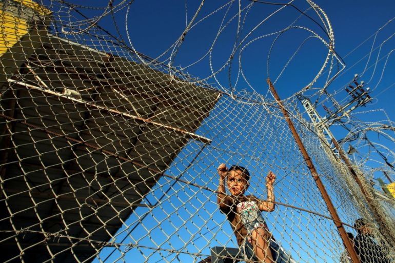 Palestinian boy stands behind a fence as he waits for his relatives to return to Gaza from Egypt through Rafah border crossing, in the southern Gaza Strip