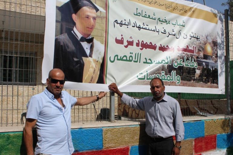 Musa Sharaf and Mahmoud Sharaf, the uncle and father of Mohammed Sharaf, stand by his poster