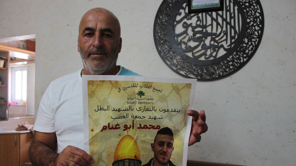 Hassan Abu Ghannem holds a poster showing his son, Mohammed, a Birzeit University student who was killed on July 21 [Nigel Wilson/Al Jazeera]