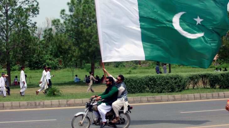 A man on the motor bike holds a national flag as he watches an air show to celebrate the 70th Independence Day in Islamabad