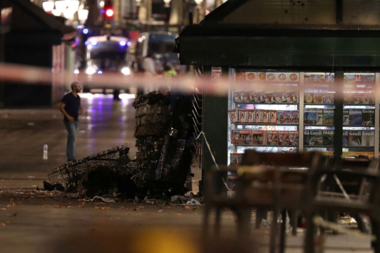 A officer walks past a fallen post cards display near the area where a van crashed into pedestrians at Las Ramblas in Barcelona