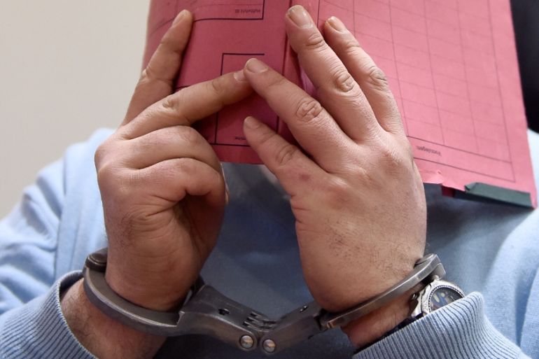 FILE PHOTO: Former nurse Niels H. masks his face with a folder on his arrival in the courtroom in Oldenburg