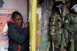 A woman cries as she stands behind policemen during clashes between supporters of opposition leader Raila Odinga and policemen, in Kibera slum, in Nairobi