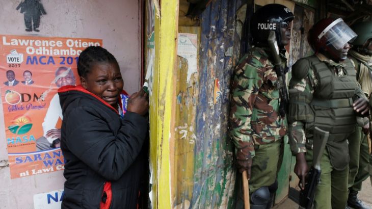 A woman cries as she stands behind policemen during clashes between supporters of opposition leader Raila Odinga and policemen, in Kibera slum, in Nairobi