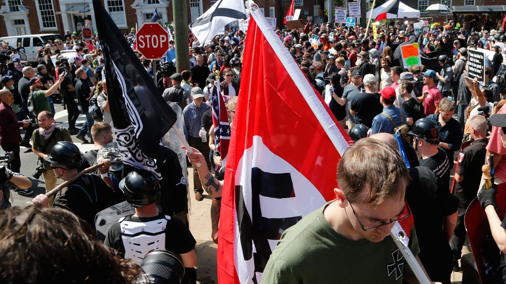 A white supremacist carrying a Nazi flag into the entrance to Emancipation Park in Charlottesville, Va. [Steve Helber/AP photo]