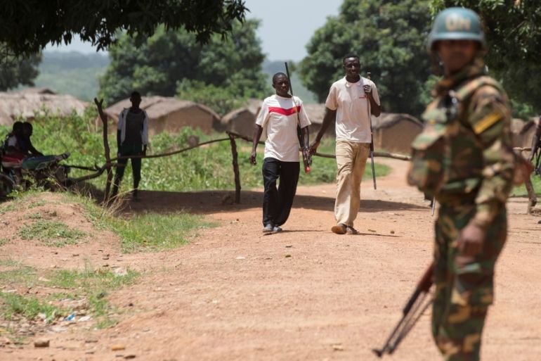 Members of the of the Anti-Balaka armed militia walk next to a United Nations peacekeeping soldier in the village of Makunzi Wali