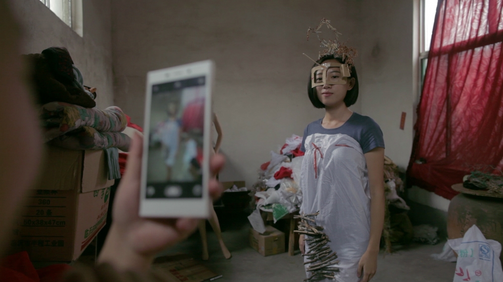 Filmmaker Rongfei Guo poses in a creation by Fairy Wang [Screengrab/Al Jazeera]
