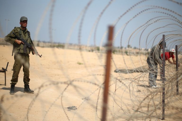 A member of the Palestinian security forces, loyal to Hamas, stands guard as men set up a barbed wire on the border with Egypt, in Rafah in the southern Gaza Strip