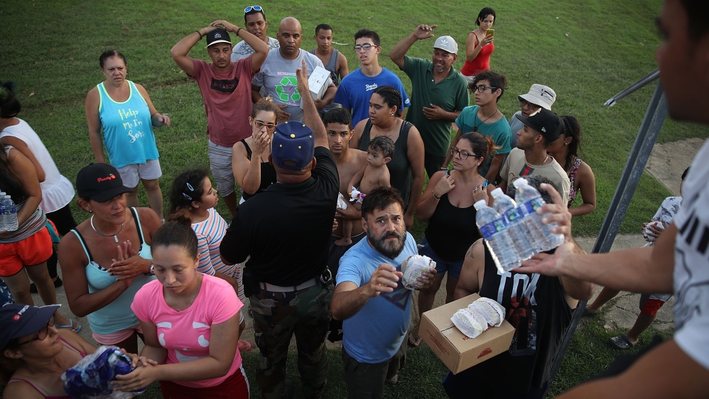 Hurricane survivors receive food and water given out by volunteers and police as they deal with the aftermath of Hurricane Maria [Joe Raedle/Getty Images]