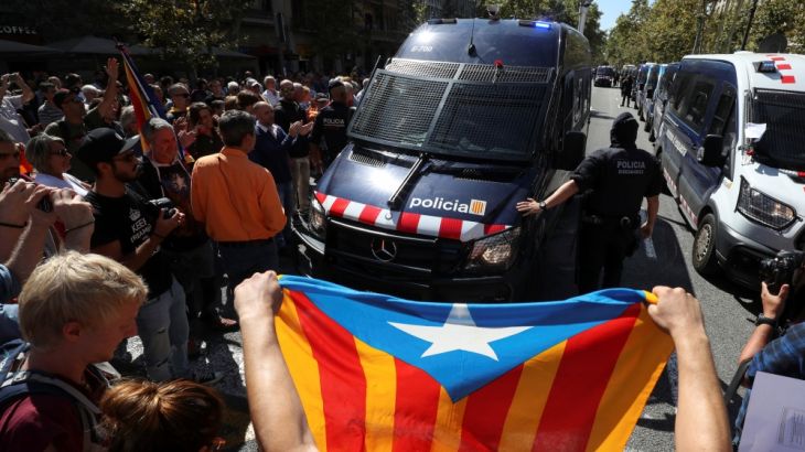 A protestor holds up an Estelada (Catalan separatist flag) in front of a Catalan police van outside the Catalan region''s economy ministry building during a raid by Spanish police on several government