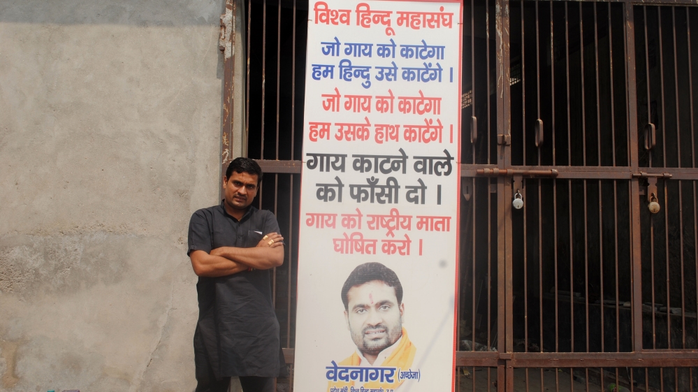 Ved Nagar stands by a poster that declares 'We will slaughter anyone who slaughters a cow' [Abhimanyu Kumar/Al Jazeera]