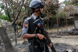 Police officer guards near a house which was burnt down during the last days of violence in Maungdaw