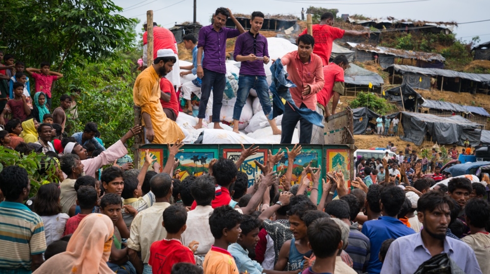 Bangladeshi volunteers throw clothes to refugees at the Balukhali new camp [Katie Arnold/Al Jazeera]