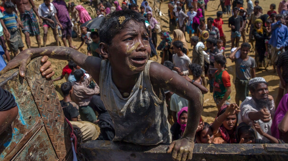 A Rohingya boy pleads with aid workers to give him a bag of rice [AP]