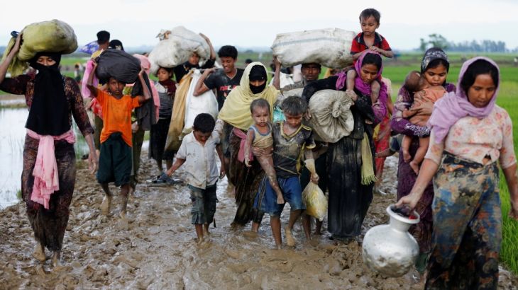 A group of Rohingya refugees walk on the muddy road after travelling over the Bangladesh-Myanmar border in Teknaf