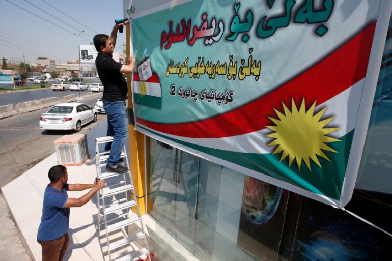 Kurdish man hangs up banner urging people to vote for independence referendum, in Erbil