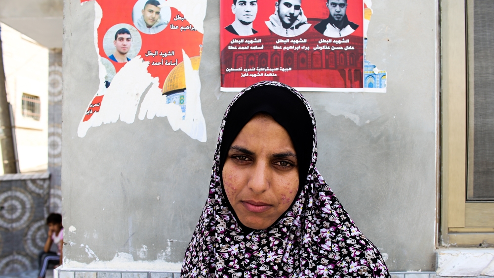 Baraa's sister, Tahani, stands next to posters of the three slain Palestinians [Jaclynn Ashly/Al Jazeera]