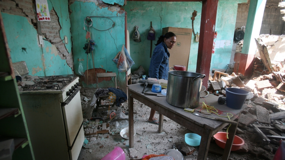 A woman stands inside her damaged home after an earthquake struck the southern coast of Mexico [Jorge Luis Plata/Reuters]