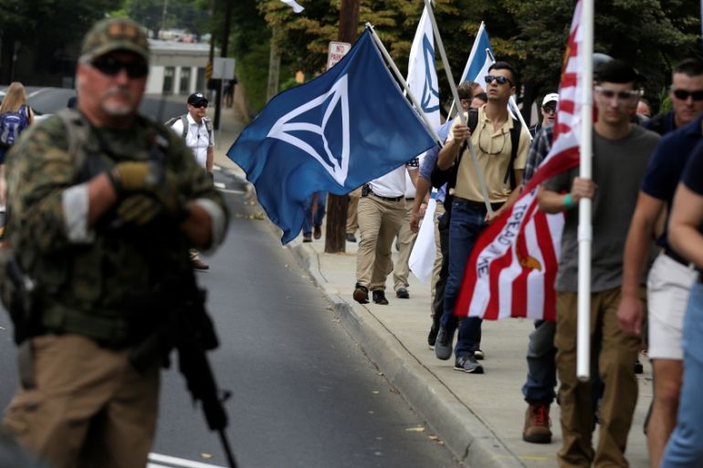 White nationalists pass a militia member as the they arrive for a rally in Charlottesville Virginia