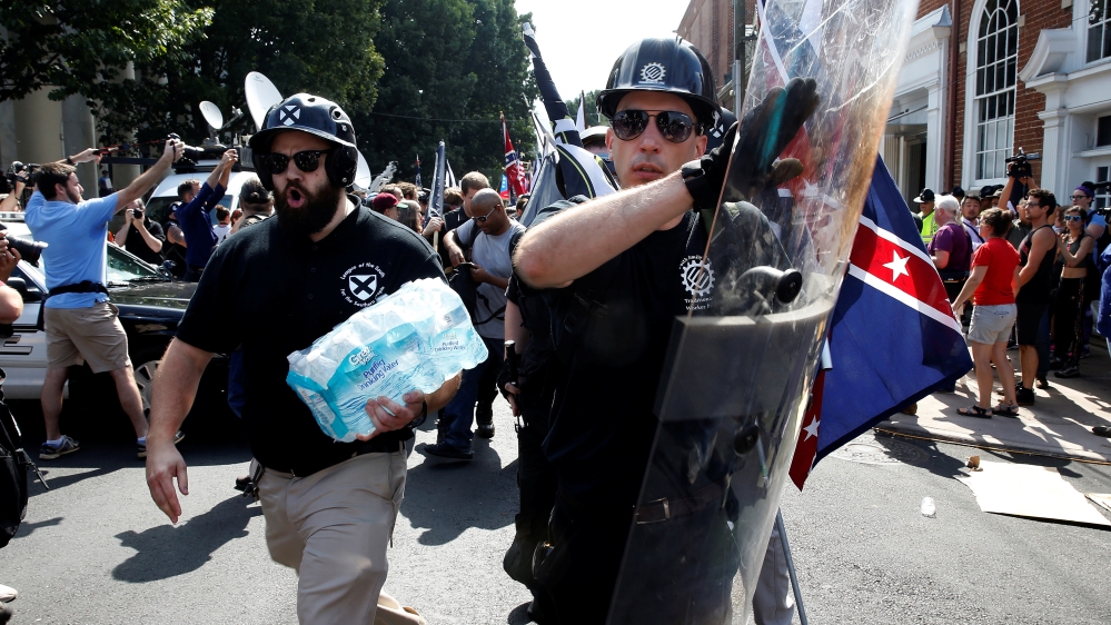 A white supremacist wearing symbols of the Traditionalist Worker Party bangs marches in Charlottesville on August 12 [File: Joshua Roberts/Reuters]