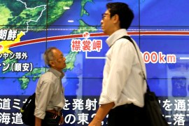 Passersby in Tokyo walk in front of a TV screen reporting news about North Korea''s missile launch
