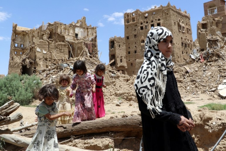 Girls stand past houses destroyed by Saudi-led air strikes in an outskirt of the northwestern city of Saada