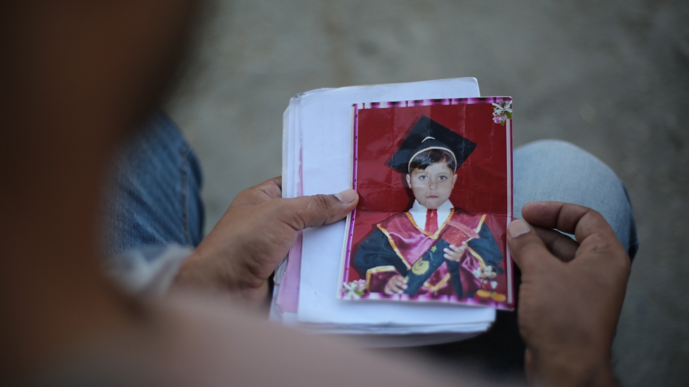 Ahmed al-Sayis looks at photos of his dead son, Mohammed [Ahmed Abdelal/Al Jazeera]