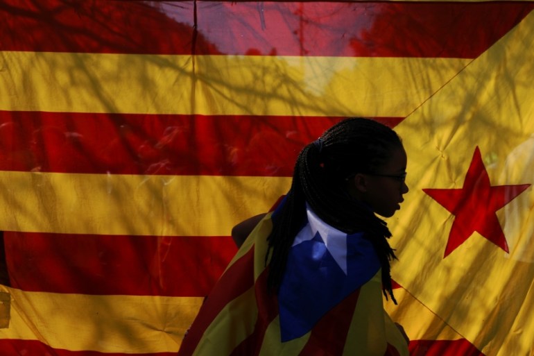 A woman wearing an Estelada (Catalan separatist flag) walks past another big Estelada during a gathering in support of the banned October 1st independence referendum in Barcelona