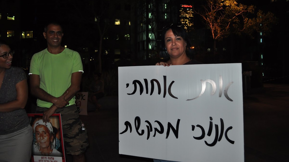 Zfira holds a sign that says: 'I am asking for my sister' [Yuval Abraham/Al Jazeera]