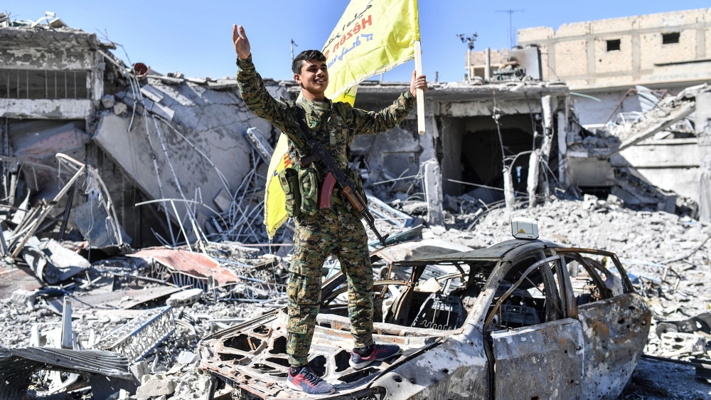 A member of the Syrian Democratic Forces holds up their flag at the iconic Al-Naim square in Raqqa [Bulent Kilic/AFP/Getty Images]
