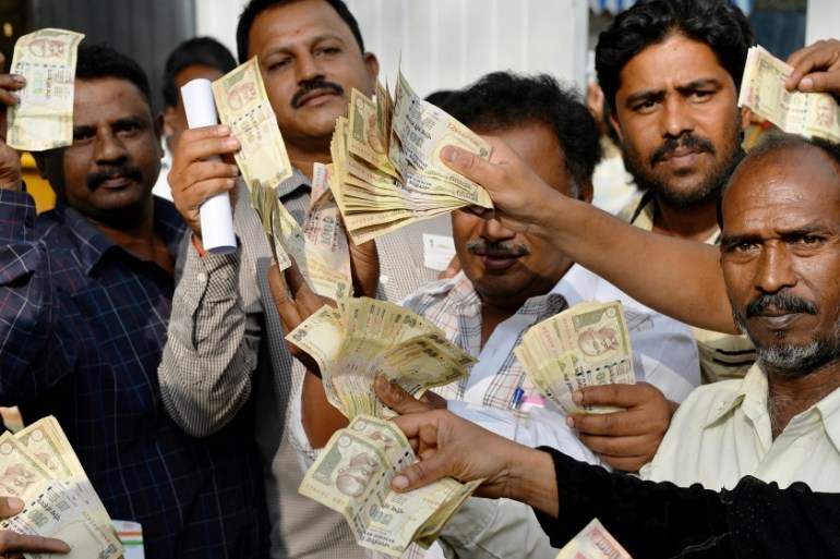 People waiting to exchange demonitised Indian currency, show their old 500 and 1000 Rupee notes near the closed gates of Reserve Bank of India in Bangalore on January 2, 2017 after acceptence of the b