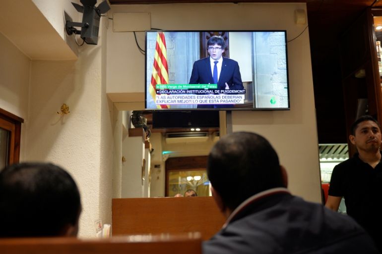 Customers at a bar watch as Catalan President Carles Puigdemont makes a televised address to the nation in Vic, Spain