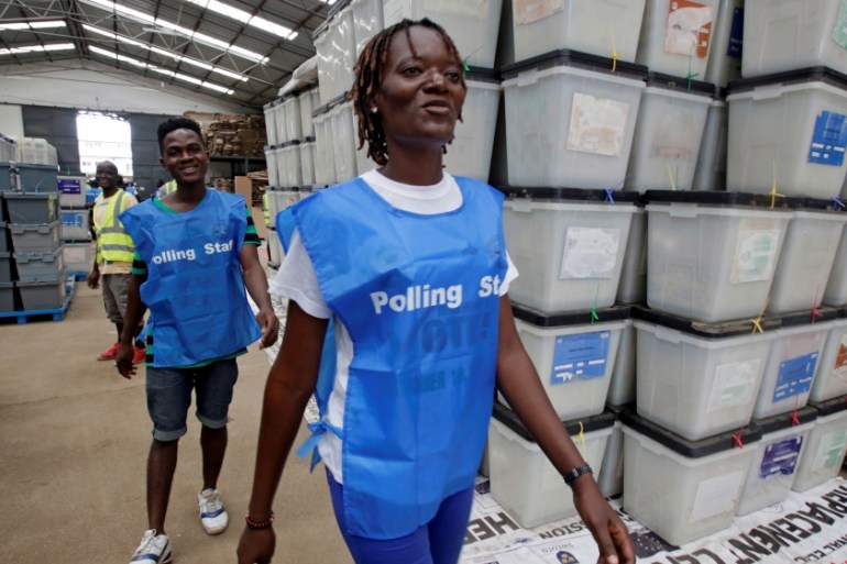 Election workers walk past ballot boxes and voting materials at the National Elections Commission headquarters in Monrovia