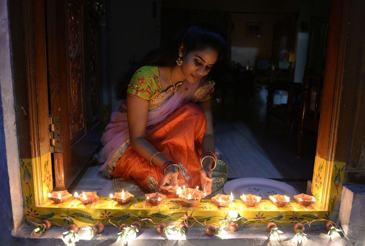 An Indian woman Nikitha places earthen lamps or ''diyas'' at the entrance of her home on the eve of Diwali Festival in Hyderabad on October 18, 2017. Diwali, the Hindu festival of lights, marks the triu