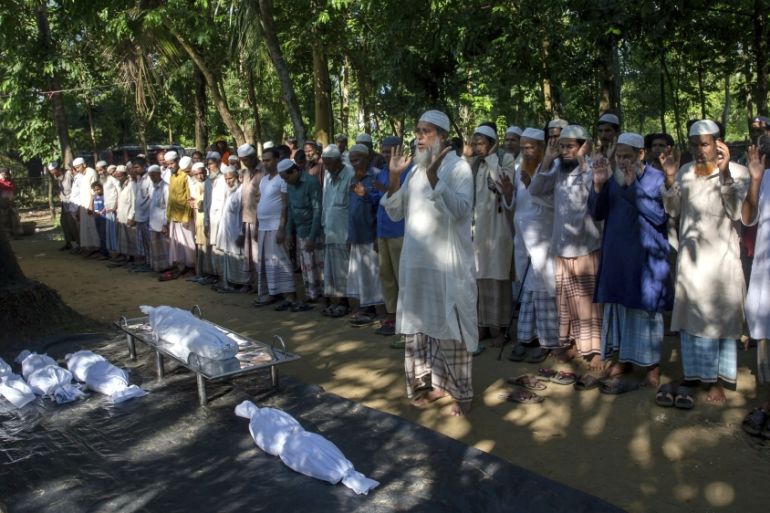 Bangladeshi villagers pray by the bodies of Rohingya Muslim children who drowned while crossing over from Myanmar into Bangladesh after their boat capsized near Shah Porir Dwip, Bangladesh, Monday, Oc