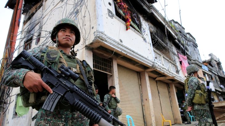 Government soldiers stand guard in front of damaged building and houses in Sultan Omar Dianalan boulevard at Mapandi district in Marawi city