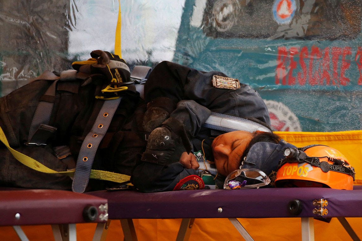 Rescue workers rest at the site of a collapsed building. REUTERS/ Carlos Jasso
