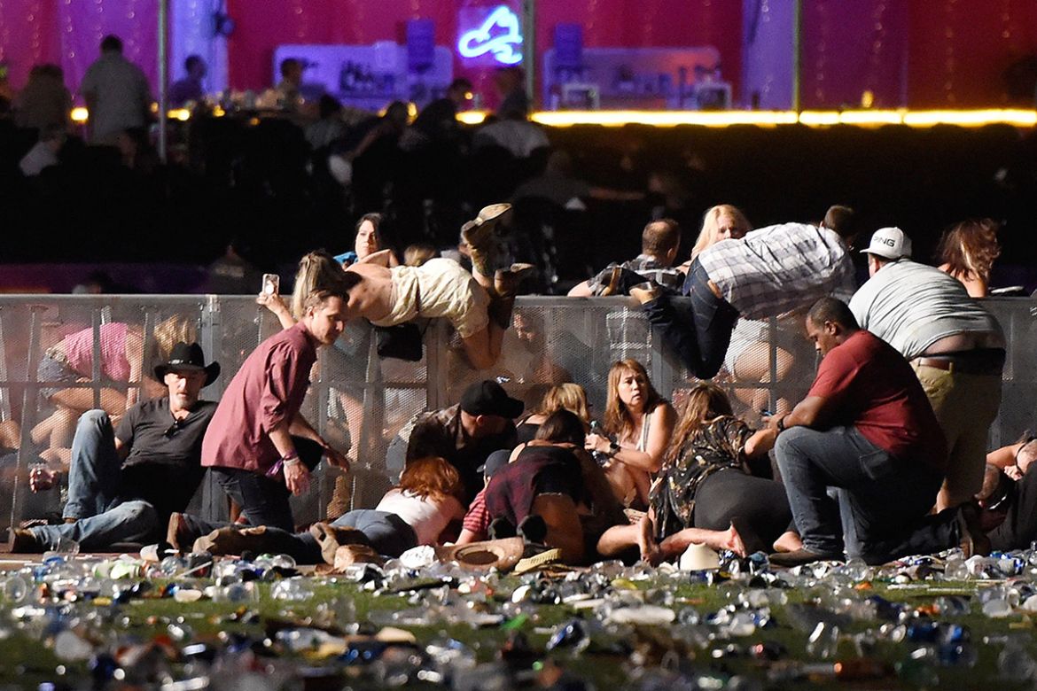 People scramble for shelter at the Route 91 Harvest country music festival after apparent gun fire was heard on October 1, 2017 in Las Vegas, Nevada. A gunman has opened fire on a music festival in La