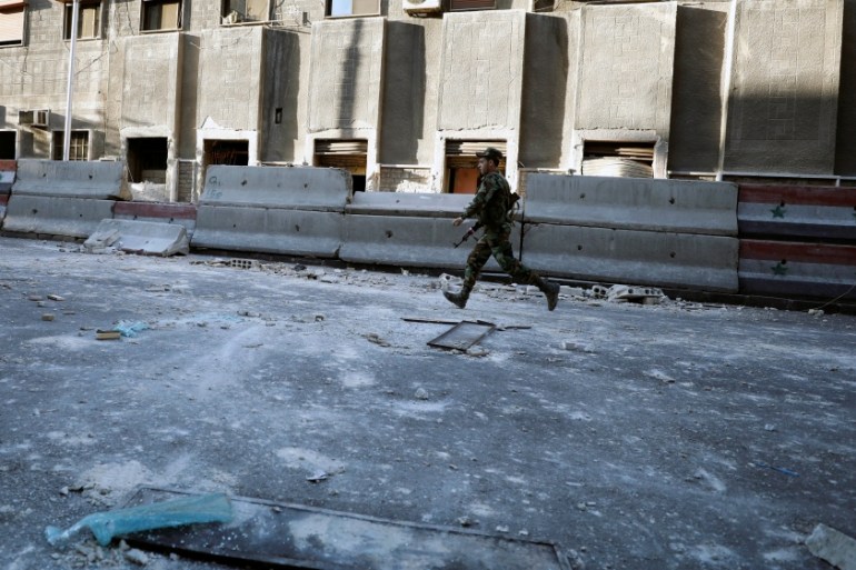 Syrian Army soldier runs near the police headquarters in central Damascus