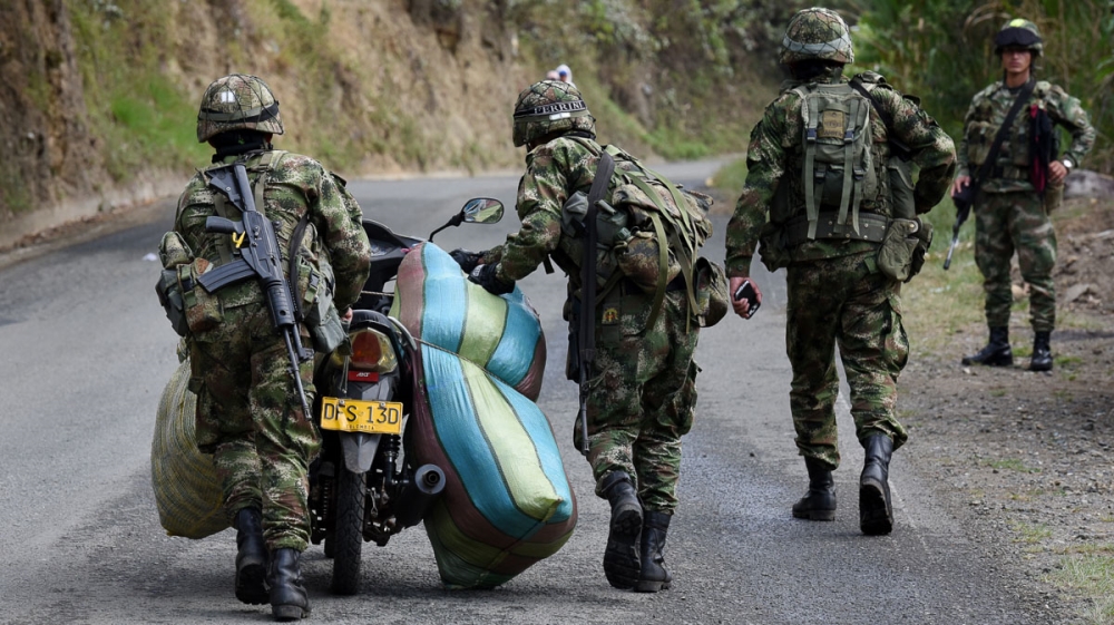 Army members push a motorcycle after confiscating two large bundles of cannabis in Toribio [Christian EscobarMora/Mira-V/Al Jazeera]