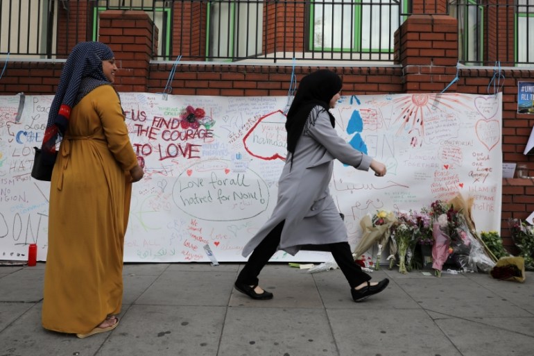 A woman walks past messages attached to a wall near the scene of an attack next to Finsbury Park Mosque, in north London