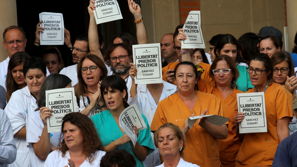 Medical workers hold up placards reading 'Freedom Political Prisoners, Sanchez, Cuixart' [Albert Gea/Reuters]