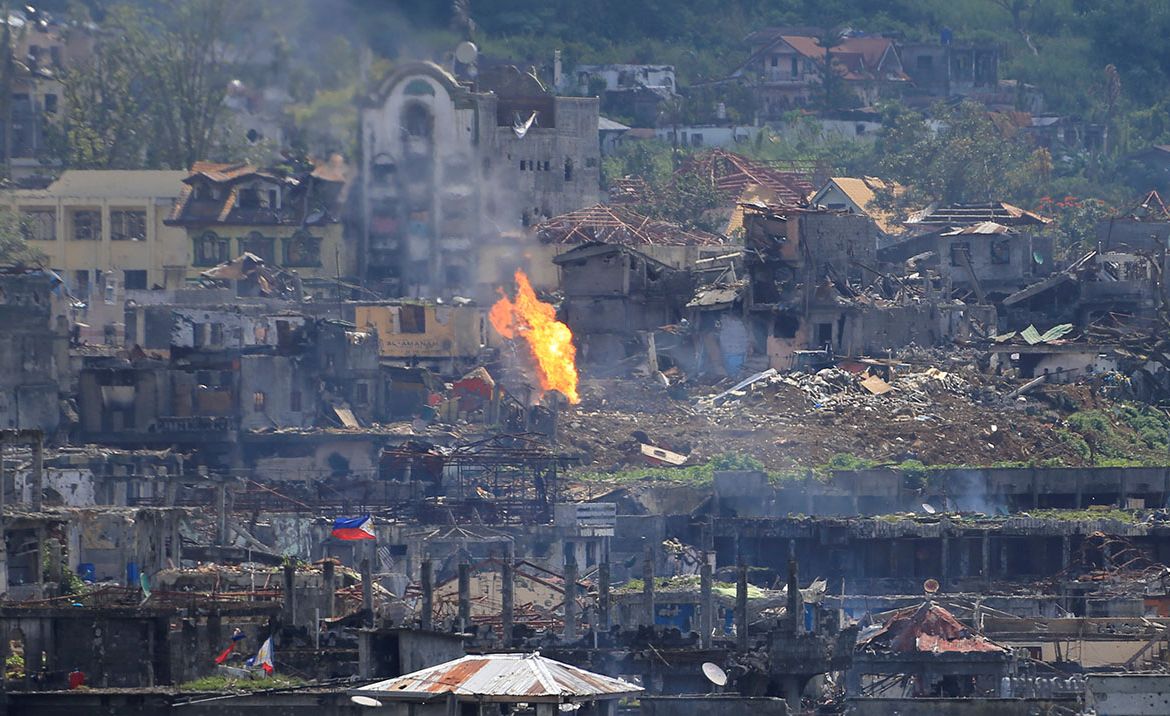 Flame rises as damaged buildings are seen after government troops cleared the area from pro-Islamic State militant groups inside a war-torn area in Marawi city, southern Philippines October 23, 2017.