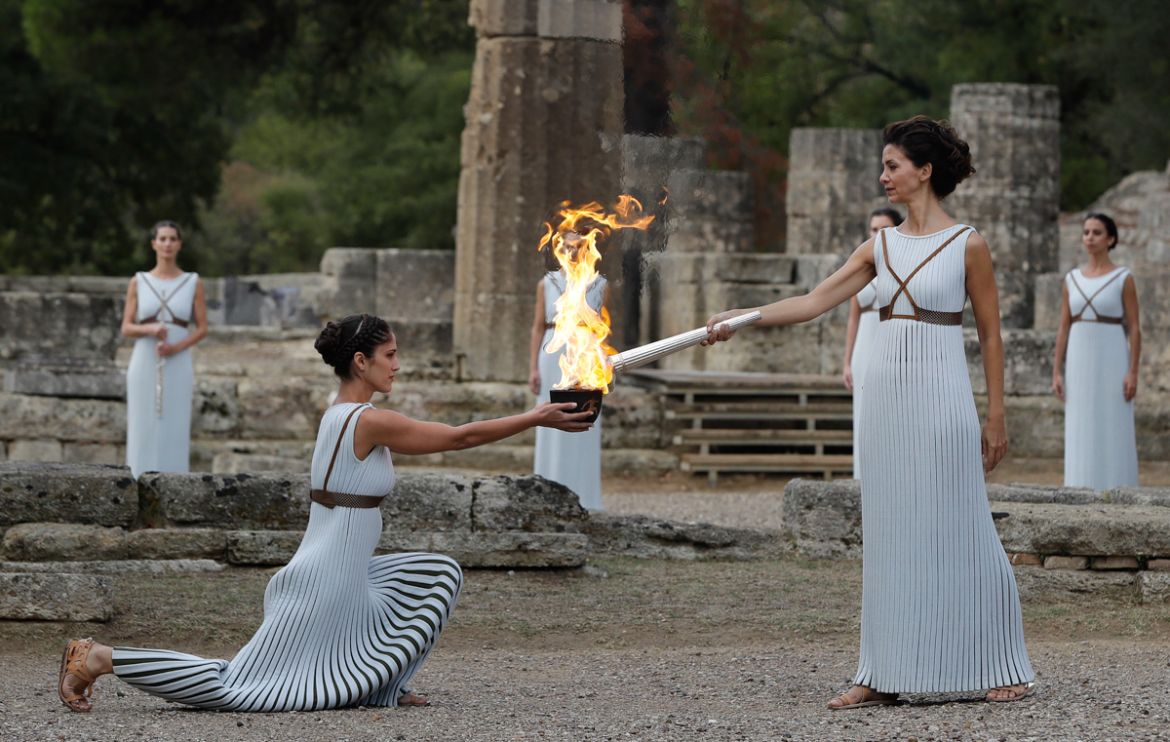 Actress Katerina Lehou, right, as high priestess, lights the torch during the lighting ceremony of the Olympic flame in Ancient Olympia, southwestern Greece, on Tuesday, Oct. 24, 2017. The flame will