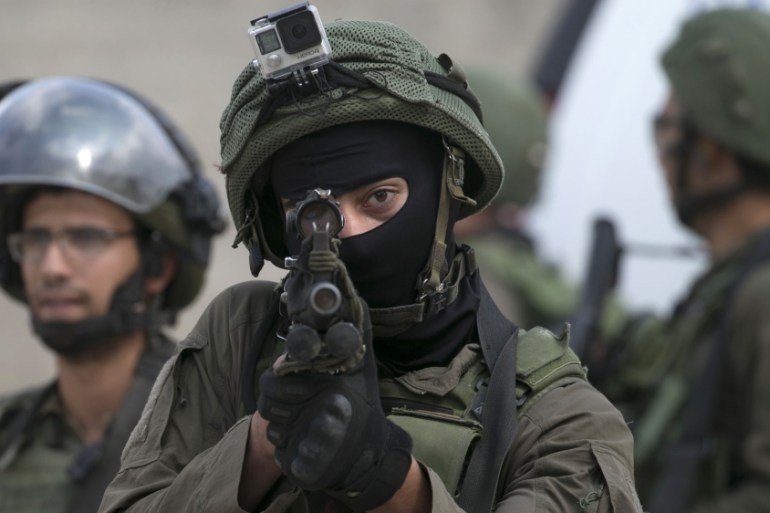 An Israeli soldier aims his weapon during clashes with Palestinian protesters following a demonstration against the expropriation of Palestinian land by Israel in the village of Kfar Qaddum, near Nabl