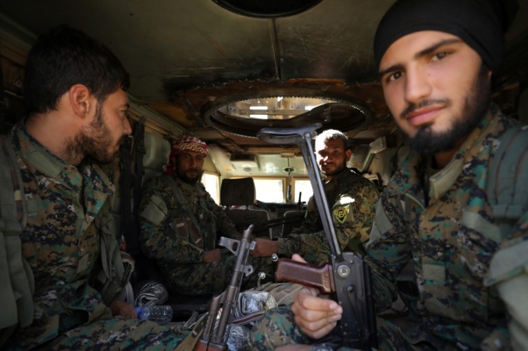 Fighters of the Syrian Democratic Forces (SDF) sit inside a vehicle in Raqqa